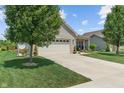 A well kept light brick home features a two car garage, long driveway, and mature trees in a community at 3420 Stoddard Pl, Indianapolis, IN 46217