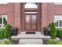 Inviting front entrance with double doors, surrounded by manicured greenery and plants at 4465 W Woodbridge Ln, New Palestine, IN 46163