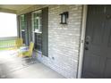 Inviting front porch with two yellow chairs and gray brick facade and front door at 6422 Hollingsworth Dr, Indianapolis, IN 46268