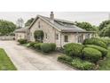 Well-maintained stone home featuring mature landscaping and a long driveway for ample parking at 6649 Madison Ave, Indianapolis, IN 46227