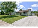 Inviting home with green siding, manicured lawn, and gravel driveway leading to a detached garage at 710 S Bancroft St, Indianapolis, IN 46203