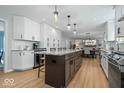 Spacious kitchen flows to dining, boasting white cabinets, a central island with seating, and hardwood floors at 8827 Lindsey Ct, Fishers, IN 46038