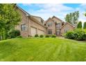 Attractive brick home featuring an attached garage, lush lawn, and classic architectural details at 1008 Westcreek Dr, Columbus, IN 47201