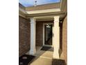 Covered front porch featuring white columns, brick facade, glass door, and modern outdoor lighting at 10477 Silver Ridge Cir, Fishers, IN 46038