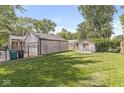 Large backyard featuring lush green grass, a detached garage, a shed, and partial fencing at 1205 Park Dr, Lebanon, IN 46052