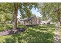 Home featuring a lush lawn, mature trees, and stone exterior, showcasing its curb appeal at 1205 Park Dr, Lebanon, IN 46052