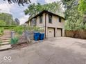 View of the side of home featuring a two-car garage, trash receptacles, and garden area at 1908 W Northgate St, Indianapolis, IN 46228
