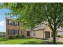 Charming home featuring a brick and vinyl exterior with a spacious three-car garage and well-maintained lawn at 301 Cobblesprings Ct, Avon, IN 46123