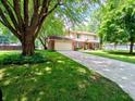 Inviting front exterior with lush lawn, mature trees, and a spacious driveway leading to the attached garage at 336 N Windsong Ln, Greenwood, IN 46142