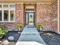 Close-up of the home's entrance showcasing brickwork, a decorative door, and flower planters at 3559 Towne Dr, Carmel, IN 46032