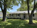 Charming home with manicured lawn, stone facade, and mature trees providing shade and curb appeal at 3906 N Lanewood Dr, Muncie, IN 47304