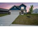 Charming two-story home with blue siding, brick accents, spacious driveway, and manicured lawn at dusk at 507 Redvine Dr, Sheridan, IN 46069