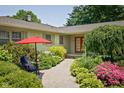 Welcoming front exterior with colorful landscaping, quaint patio seating, and charming architectural details at 7401 N Layman Ave, Indianapolis, IN 46250