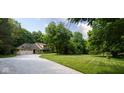 The charming yellow home is nestled amongst lush trees, featuring a well-manicured lawn and a long, winding driveway at 9722 N Gasburg Rd, Mooresville, IN 46158