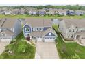 Aerial view of a light blue, two-story home in a well-kept suburban neighborhood with a pond at 5473 Forest Glen Dr, Brownsburg, IN 46112