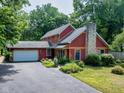 Charming two-story home with a stone chimney, attached garage, and professionally landscaped yard at 5631 Shelby St, Indianapolis, IN 46227