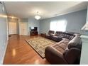 Open-concept living space with wood flooring, a crystal chandelier, and comfortable sectional at 621 Appleseed Way, Indianapolis, IN 46217