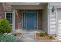 Close-up of the front door, showcasing a blue door, brick facade, and landscaped walkway at 6562 Quail Run, Fishers, IN 46038
