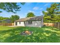Spacious backyard featuring a fire pit, fenced yard, and a well-maintained lawn at 7239 N Orchard Dr, Indianapolis, IN 46236