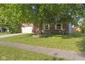 Brick home featuring a well-manicured lawn, two-car garage, and mature shade tree at 7239 N Orchard Dr, Indianapolis, IN 46236