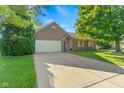 Charming brick home with an attached two-car garage and long driveway on a sunny, clear day at 7239 N Orchard Dr, Indianapolis, IN 46236