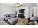 Comfortable living room featuring hardwood floors, ceiling fan, and ample seating with a large screen television at 7307 Twin Beech Dr, Indianapolis, IN 46226