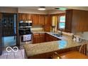 Traditional kitchen features wood cabinets, granite countertops, and stainless steel appliances at 7334 Fairwood Cir, Indianapolis, IN 46256