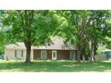 Charming tan and brown house with well-maintained lawn and mature trees in a quiet, residential neighborhood at 7966 Chiltern Dr, Indianapolis, IN 46268