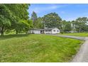 Traditional white brick ranch-style home with an attached garage, lush lawn, and mature trees on a sunny day at 8105 Allisonville Rd, Indianapolis, IN 46250
