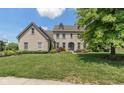 Charming two-story brick home with a manicured front lawn and a welcoming blue front door at 8754 Lily Ct, Zionsville, IN 46077