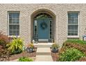 A charming front entrance with a blue door framed by an arched brickway and decorative plants at 8754 Lily Ct, Zionsville, IN 46077