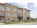 Brick townhome featuring a balcony, stylish windows, and a landscaped front yard on a sunny day at 1461 Whistle Way, Westfield, IN 46074