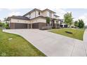 Long concrete driveway leading to a three-car garage, with manicured lawn and landscaping at 20450 Chatham Hills Blvd, Westfield, IN 46074