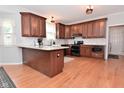 Open kitchen featuring wooden cabinetry, stainless steel appliances, granite countertops, and hardwood floors at 6118 Yellow Birch Ct, Avon, IN 46123