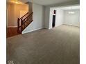 A view of stairs and a carpeted living room with adjacent dining room and hardwood hallway at 6632 Coppel Ct, Indianapolis, IN 46259
