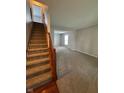 A view of stairs leading upstairs and a carpeted living room with adjacent dining room at 6632 Coppel Ct, Indianapolis, IN 46259
