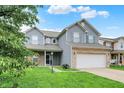 Charming two-story home featuring blue siding, brick accents, well-manicured lawn, and an attached two-car garage at 8212 Twin River Dr, Indianapolis, IN 46239