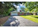 Charming brick home with an attached garage, mature trees, and a large driveway with ample parking at 1231 N Graham Ave, Indianapolis, IN 46219