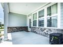 Covered porch featuring vinyl siding, brick base, windows, a glass paneled door, and concrete flooring at 14404 Stairbridge Pl, Carmel, IN 46074
