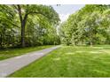 Sprawling lush green yard with mature trees and a paved walkway at 1616 W 116Th St, Carmel, IN 46032