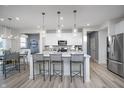 Modern open kitchen boasts stainless steel appliances, gray-toned floors, and a central island with barstools at 18980 Seaforth Way, Westfield, IN 46074