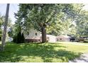 Home featuring a brick facade, siding, driveway, well-maintained lawn, and mature trees at 218 Narcissus Dr, Indianapolis, IN 46227
