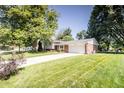 Charming home with brick facade, siding, driveway, well-maintained lawn, mature trees, and landscaping at 218 Narcissus Dr, Indianapolis, IN 46227