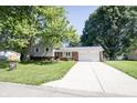 Charming home with brick facade, siding, driveway, well-maintained lawn, and mature trees at 218 Narcissus Dr, Indianapolis, IN 46227