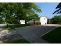 View of the side of this split-level home showcasing its pea gravel driveway and mature trees at 2606 Shakespeare Dr, Southport, IN 46227