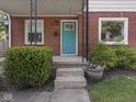 Close-up of a charming front porch with a vibrant blue door, steps, and lush landscaping at 4523 Kingsley Dr, Indianapolis, IN 46205