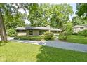 A single story home with a chimney, stone driveway and beautiful lawn surrounded by lush trees at 6430 N Rural St, Indianapolis, IN 46220