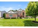 Well-manicured lawn and mature landscaping highlight this two-story brick home, complete with an arched entryway at 11995 Gray Eagle Dr, Fishers, IN 46037