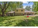 Spacious backyard featuring mature trees and the exterior of the home with stone accents at 1930 Bechtel Rd, Indianapolis, IN 46260