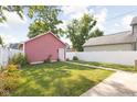 Lush backyard with a well-manicured lawn, white fence, and a detached garage at 2015 N College Ave, Indianapolis, IN 46202